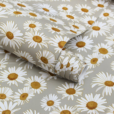 A roll of Tempaper's Daisies floral peel-and-stick wallpaper resting on a panel with the same design.