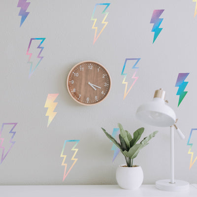 Holographic Lightning Bolts wall decals from Tempaper on a wall with a clock and behind a desk with a plant and light.