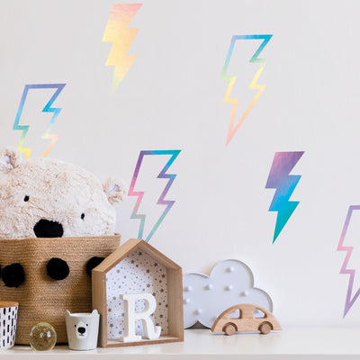 Kids play toys seated on a white cabinet with a wall decorated used Tempaper's holographic Lightning Bolt wall decals.