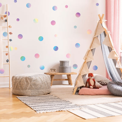 A child's play area decorated with a teepee and holographic Dots wall decals from Tempaper on the wall.