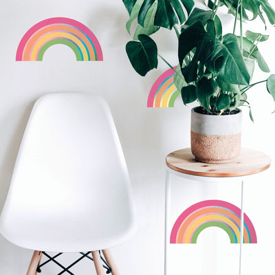 A chair and side table with a plant next to a wall decorating using Rainbow wall decals from Tempaper.