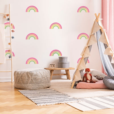 A child's play area with rugs and a teepee with Rainbow wall decals from Tempaper scattered on the wall.