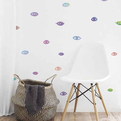 Holographic You Are Seen wall decals from Tempaper on a white wall with a white chair and basket.