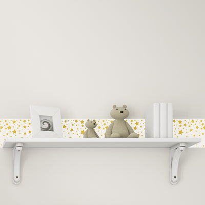 Tempaper's Falling Stars Border Peel And Stick Wallpaper in white and gold shown above a shelf.