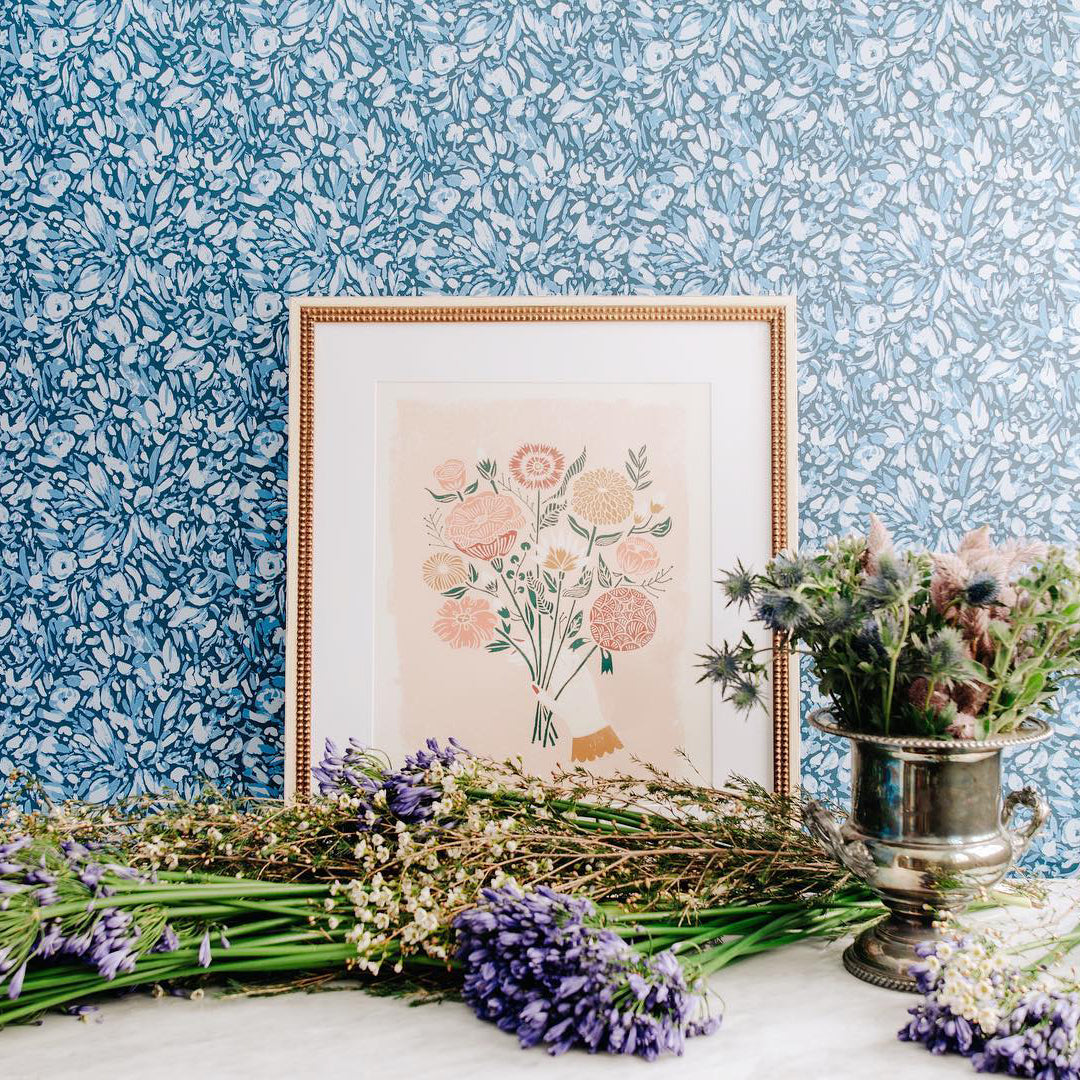 Tempaper's Flamboyan Peel And Stick Wallpaper By She She shown behind plants and a picture frame.