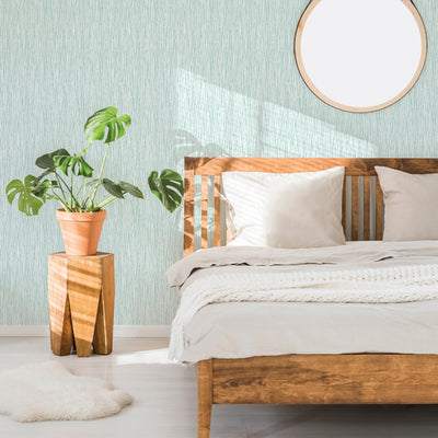 A bedroom with a wood bed frame and plant featuring Tempaper's String of Pearls Removable Wallpaper in green.