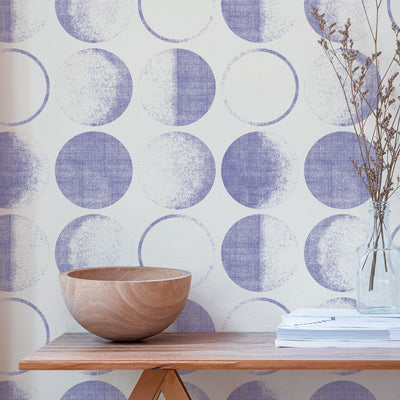 A wood table and Tempaper's Moons Temporary Wallpaper in a periwinkle colorway.