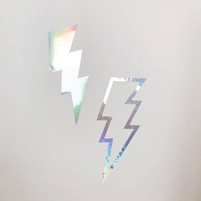 Two holographic Lightning Bolts wall decals from Tempaper on a wall, one is solid and another is outlined in holographic with the center open.