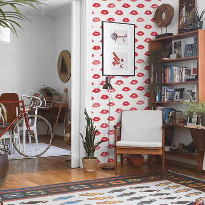Painted Lips Removable Wallpaper - A wood chair, bicycle, rug, and bookcase in a room featuring Painted Lips Peel And Stick Wallpaper by Novogratz | Tempaper