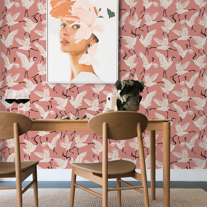 Tempaper's Family of Cranes Peel And Stick Wallpaper By Novogratz shown behind a table and chairs. #color_dusty-rose