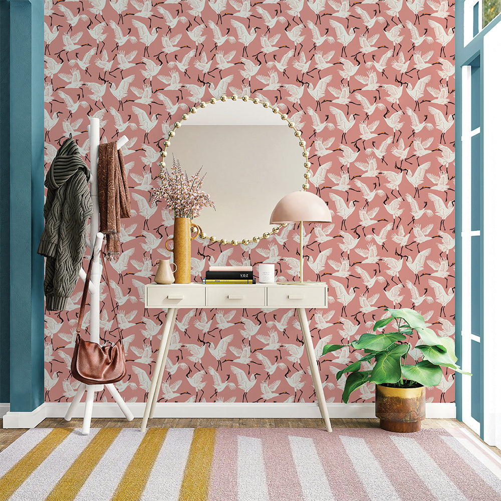 Tempaper's Family of Cranes Peel And Stick Wallpaper By Novogratz shown above a desk behind a mirror and plant. #color_dusty-rose