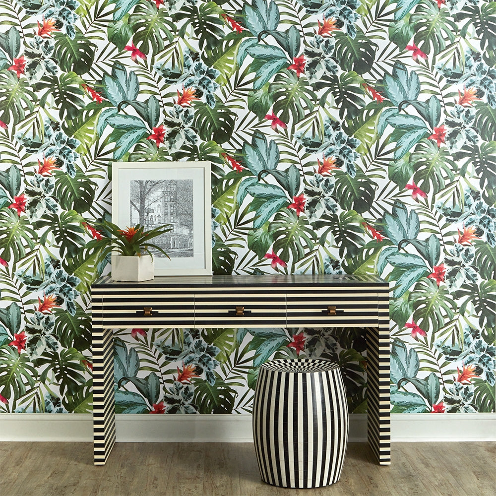 A black and white striped side table and matching stool with Rainforest removable wallpaper from Tempaper on the wall.