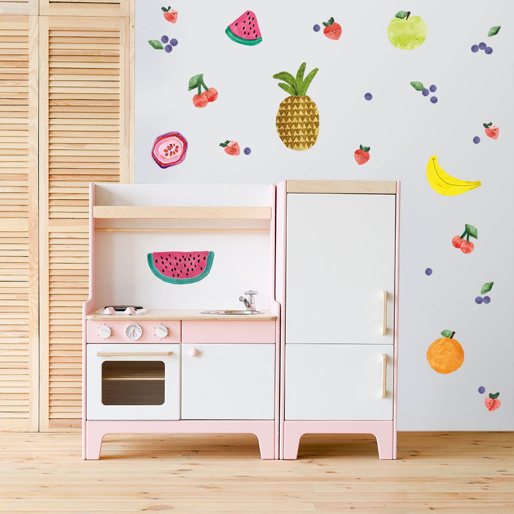 Tempaper's Fruit Salad Wall Decals shown on a wall behind a kids oven set.