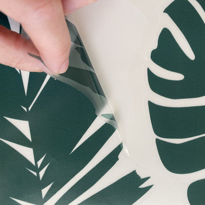 A person peeling Tempaper's Graphic Palm Leaf Wall Decals.