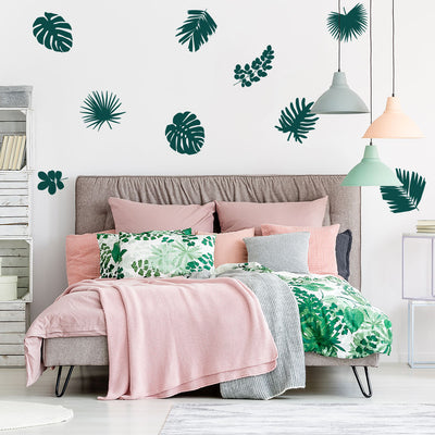 Tempaper's Graphic Palm Leaf Wall Decals in a bedroom behind a bed.
