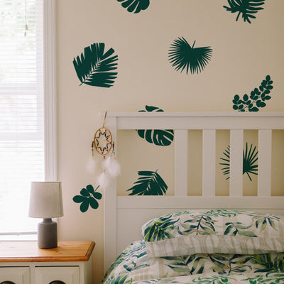 Tempaper's Graphic Palm Leaf Wall Decals in a bedroom behind a white headboard and wood nightstand.