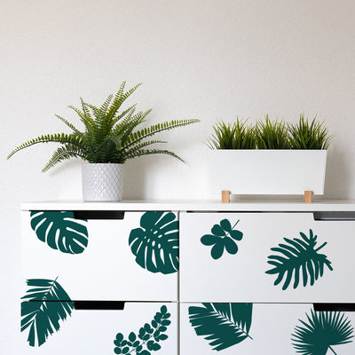 Tempaper's Graphic Palm Leaf Wall Decals on a white dresser with two plants on top.