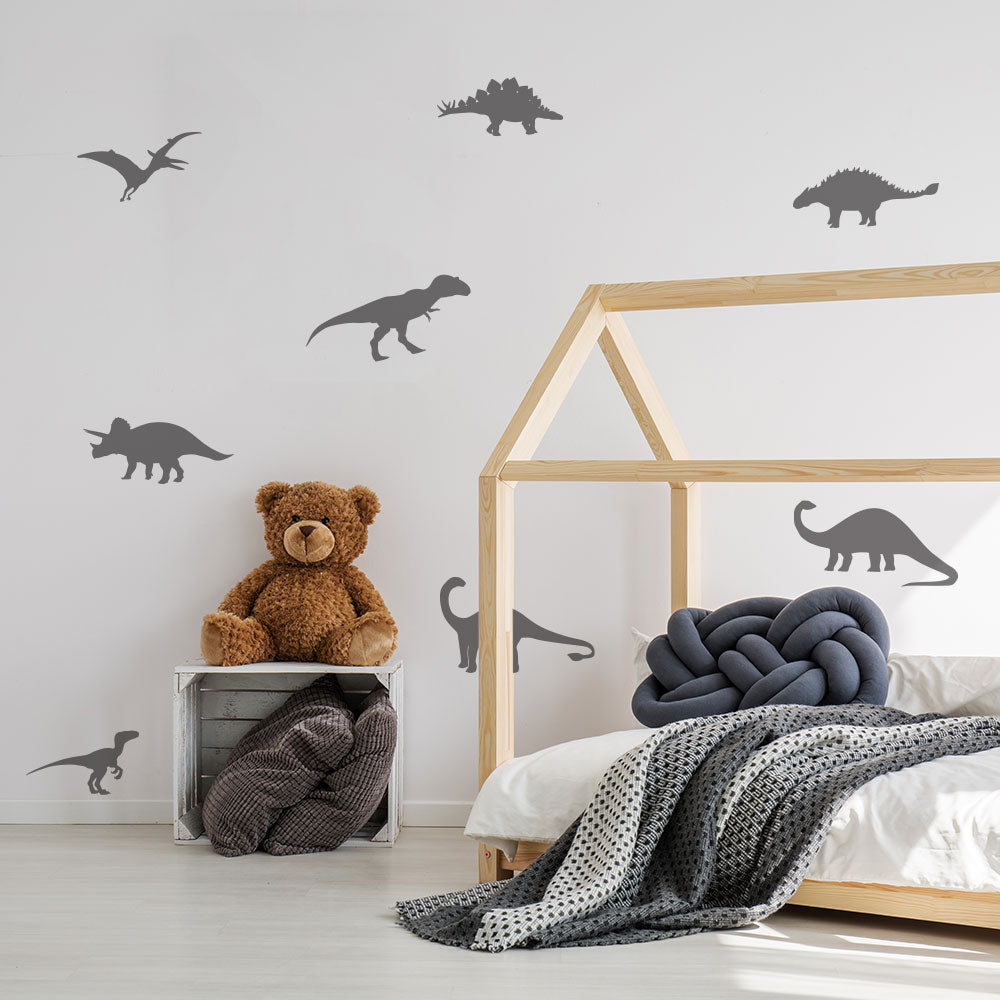 Tempaper's Dinosaur Wall Decals shown in a kids bedroom behind a bed.
