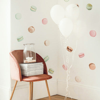 A corner with a pink velvet chair, a bunch of white balloons, and Tempaper's French Macaron wall decals decorating the wall!