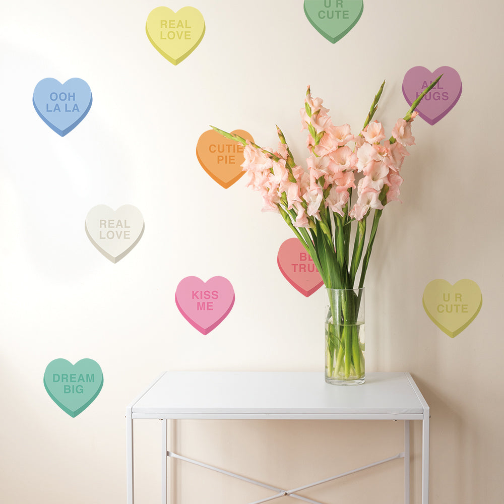 A white table with a vase of flowers showing off Tempaper's Candy Heart wall decals on the wall behind.