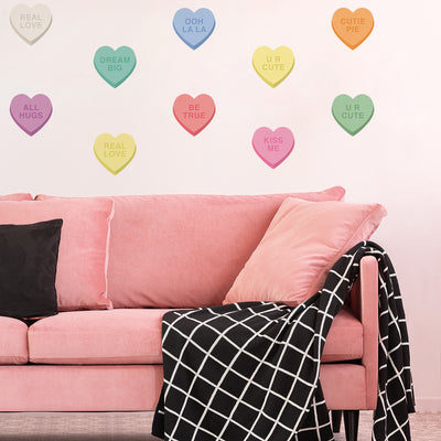 A pink velvet couch with a black and white blanket and Tempaper's Candy Heart wall decals.