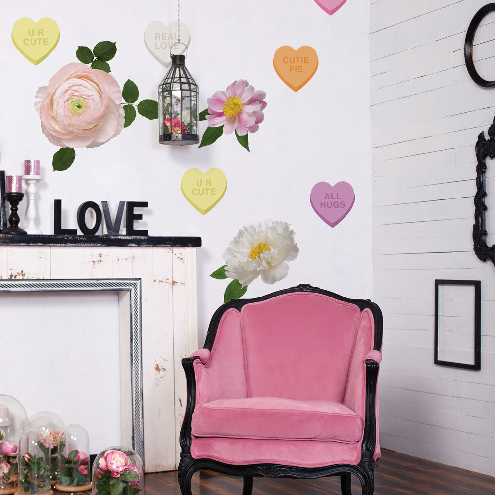 A cute seating area with a pink velvet chair next to a fireplace and a wall decorated using Tempaper's Candy Heart and Large Flower wall decals. 