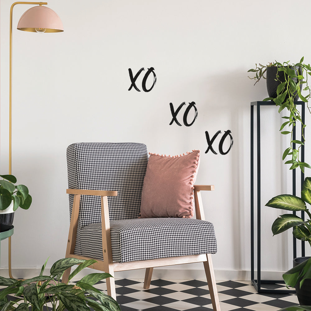 A plant room with checkered floor, black and white chair, and Tempaper's black XOXO wall decals on the wall behind.