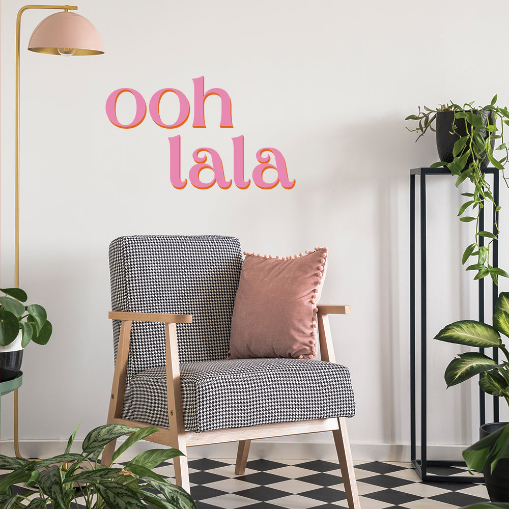 Tempaper's pink Ooh La La wall decals on the wall in plant room with checkered flooring and a black and white chair.