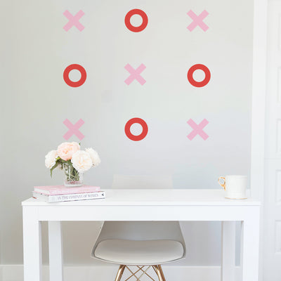 Pink and red Tic Tac Toe wall decals from Tempaper decorating the wall of an office space with a white desk and white desk chair.