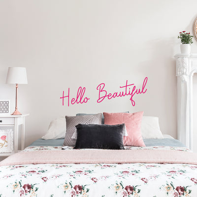 Tempaper's Hello Beautiful wall decal on the wall behind a white bed with a white nightstand.