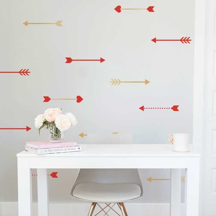 Tempaper's Cupid's Arrows wall decals on the wall behind a white desk and desk chair chair with a vase of flowers and coffee mug. 