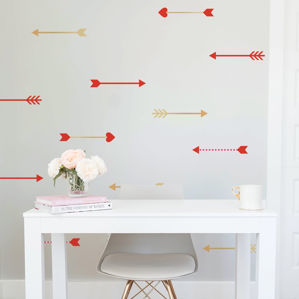 Tempaper's Cupid's Arrows wall decals on the wall behind a white desk and desk chair chair with a vase of flowers and coffee mug. 