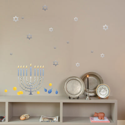 Tempaper's Festival of Lights Wall Decal shown above a bookcase behind plates and a candle.