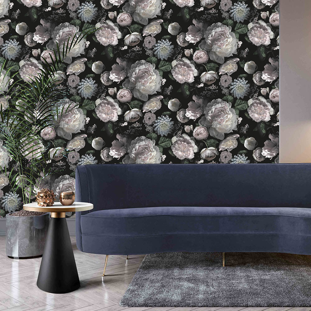 A long velvet sofa with a rug, palm plant, side table, and wall accented using Moody floral peel-and-stick wallpaper from Tempaper.