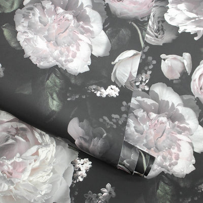 A roll of Moody floral peel-and-stick wallpaper from Tempaper rolled over a second panel of wallpaper with the same design.