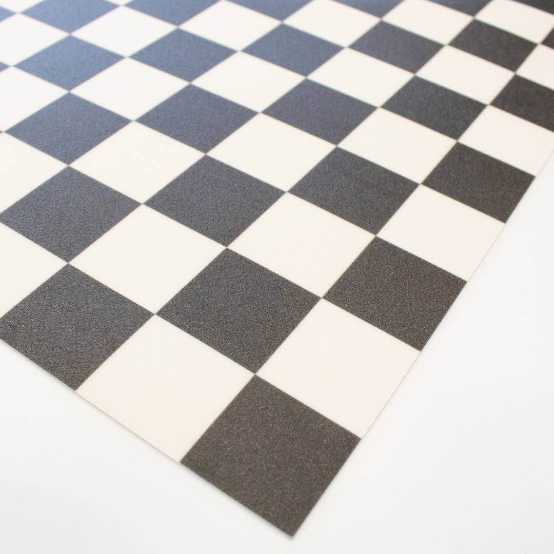 A up close corner of Tempaper's Checkmate Vinyl Rug in black and white.#color_domino