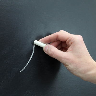 Someone drawing a line of chalk on Tempaper's chalkboard wallpaper.
